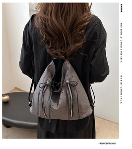 Detail of gray canvas backpack with red polka dots and back vertical zipper pockets