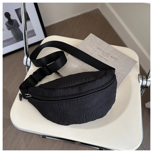Detail of minimalist black crossbody chest bag with pleated texture and adjustable strap