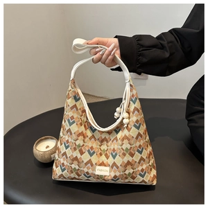 Close-up of geometric pattern nylon tote bag with beaded charm and leather logo tag
