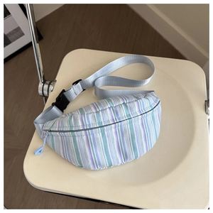Détail du sac ceinture en toile rayée avec sangle réglable et boucle sur une chaise