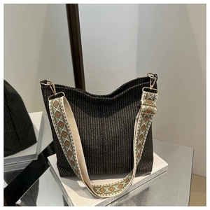 Detail of grey woven bucket bag with beige jacquard strap and gold metal buckles