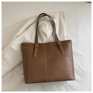 Gros plan du sac cabas marron montrant les coutures contrastées et les bandoulières réglables
