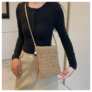 Detail of bohemian straw crossbody bag featuring hollow-out pattern and long tassel detail