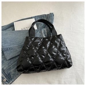 Détail du sac fourre-tout noir matelassé avec finition brillante et larges anses