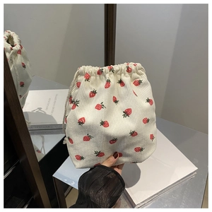 Détail d'une pochette en velours côtelé blanc à imprimé fraises rouges