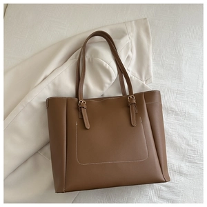 Détail d'un sac cabas en cuir mat marron avec coutures blanches et boucle en métal