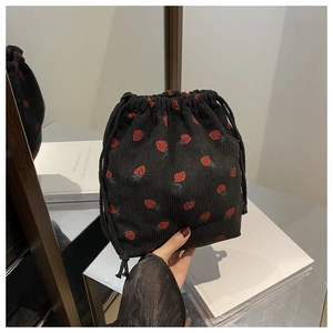 Détail de broderie fraise sur un sac à bandoulière en velours côtelé noir à cordon