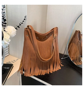 Close-up of brown litchi leather tote bag with long bohemian fringes and gold hardware