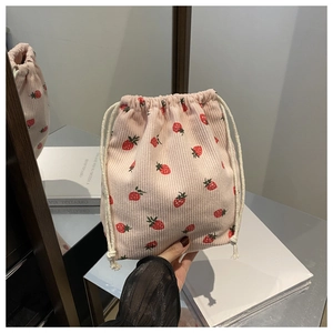Vue détaillée d'une pochette à cordon en velours rose avec motifs de fraises rouges