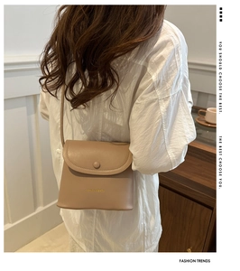 Lifestyle shot of a beige mini crossbody bag featuring a classic flap and snap closure
