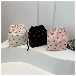 Three-piece set of strawberry print drawstring bags in cream, black, and pink corduroy