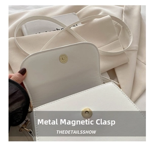 Close-up of the high-quality hardware magnetic buckle on a white leather shoulder bag