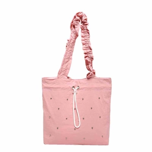 Pink drawstring tote bag with decorative studs and pleated handles on white background