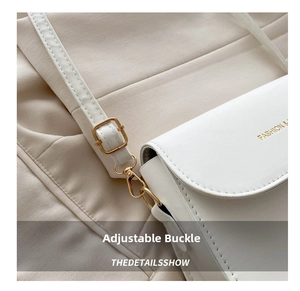 Detail of white leather shoulder bag with gold metal buckle and Fashion text engraving