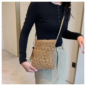 Detail of hand-woven straw crossbody bag with floral crochet pattern and tassel
