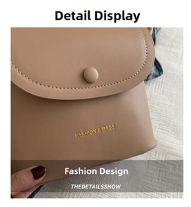 Detailed close-up of light brown leather crossbody bag with gold text and stitching