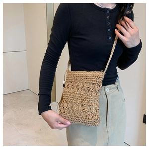 Detail of bohemian straw crossbody bag with floral hollow knit pattern for beach vacations