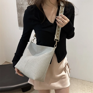 Chic woven bucket bag with patterned wide strap shown from a 45-degree angle