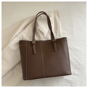 Gros plan du sac cabas marron avec surpiqûres contrastées et détails dorés chics