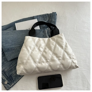 Gros plan sur un sac cabas matelassé blanc avec anses noires et accessoires denim