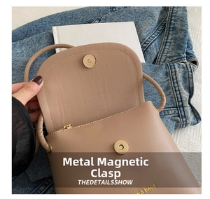 Close-up of golden magnetic snap button on minimalist khaki leather crossbody bag