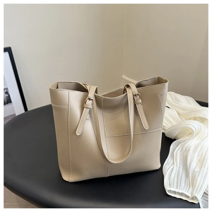 Vue détaillée du sac cabas en cuir beige texturé sur support noir avec bandoulière réglable