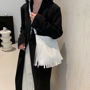 White vintage tassel tote bag with gold studs on a model wearing a black blazer coat