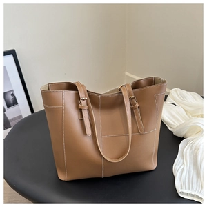 Détail du cabas marron avec surpiqûres blanches et boucles réglables en métal doré
