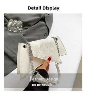 Gros plan du sac asymétrique blanc avec texture crocodile et bandoulière chaîne argentée