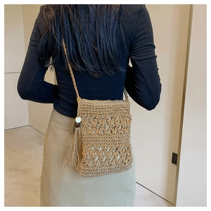 Detail of woven straw bucket bag showing intricate hollow texture and tassel accents