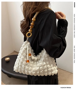 Détail du sac blanc en tissu gaufré avec bandoulière en perles de bois et cordon de serrage