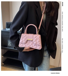 Détail du sac à main rose matelassé avec fermoir doré porté sur un blazer noir