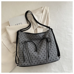 Detail of grey heart print tote bag with silver zippers and black ribbon bows decoration