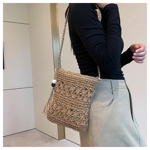 Detail of bohemian straw bag featuring hollow floral patterns and fringe tassel accents