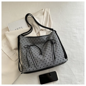 Detail of grey tote bag featuring heart patterns, bow zippers, and spacious front pockets