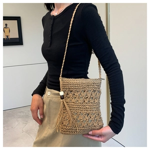 Detail of bohemian straw bag featuring hollow crochet patterns, tassels and beads