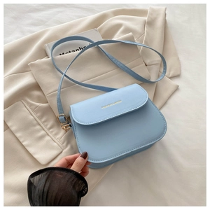Detail of light blue leather saddle bag featuring golden stamp logo and adjustable strap