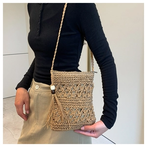 Detail of star-patterned straw crossbody bag with decorative beads and long tassels