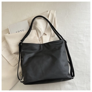 Detailed top view of a large black tote bag on cream fabric with a matching blazer
