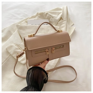Détail d'un sac à main beige avec doubles fermetures éclair et verrous dorés décoratifs