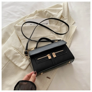 Détail du sac bandoulière noir avec double fermeture éclair et verrous dorés sur cuir texturé