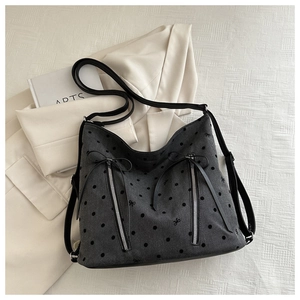 Detail of gray polka dot tote bag with silver zippers and black leather strap