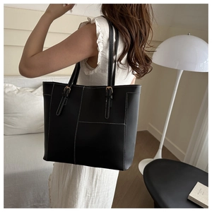 Sac fourre-tout noir porté épaule avec surpiqûres blanches et détails dorés chic