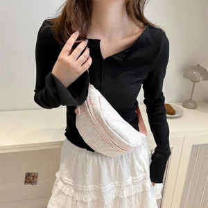 Pink and white textured crescent fanny pack crossbody bag worn by a model in lifestyle setting