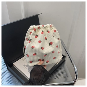 Détail du sac à cordon en velours côtelé crème avec imprimés fraises et texture douce