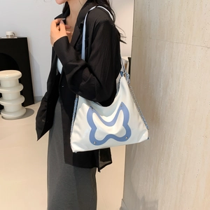 Weiße Schultertasche mit Schmetterlings-Patch und Silberkette am Modell