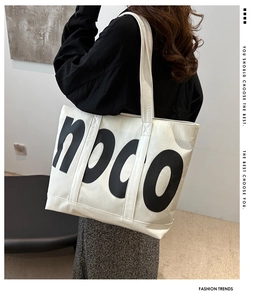 Close-up of white canvas tote bag with bold black NPCO lettering and wide shoulder strap