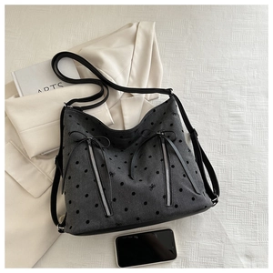 Detail of grey denim tote bag featuring black polka dots and vertical zippers on front