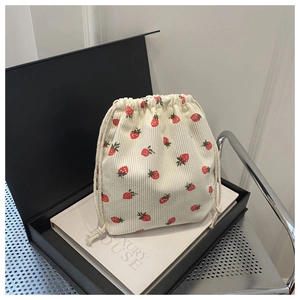 Détail du sac à cordon en velours crème avec imprimé fraises sur boîte cadeau