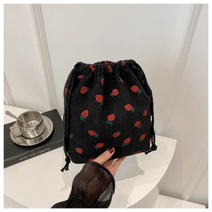 Gros plan du sac seau noir en velours côtelé avec motif de fraises rouges imprimé